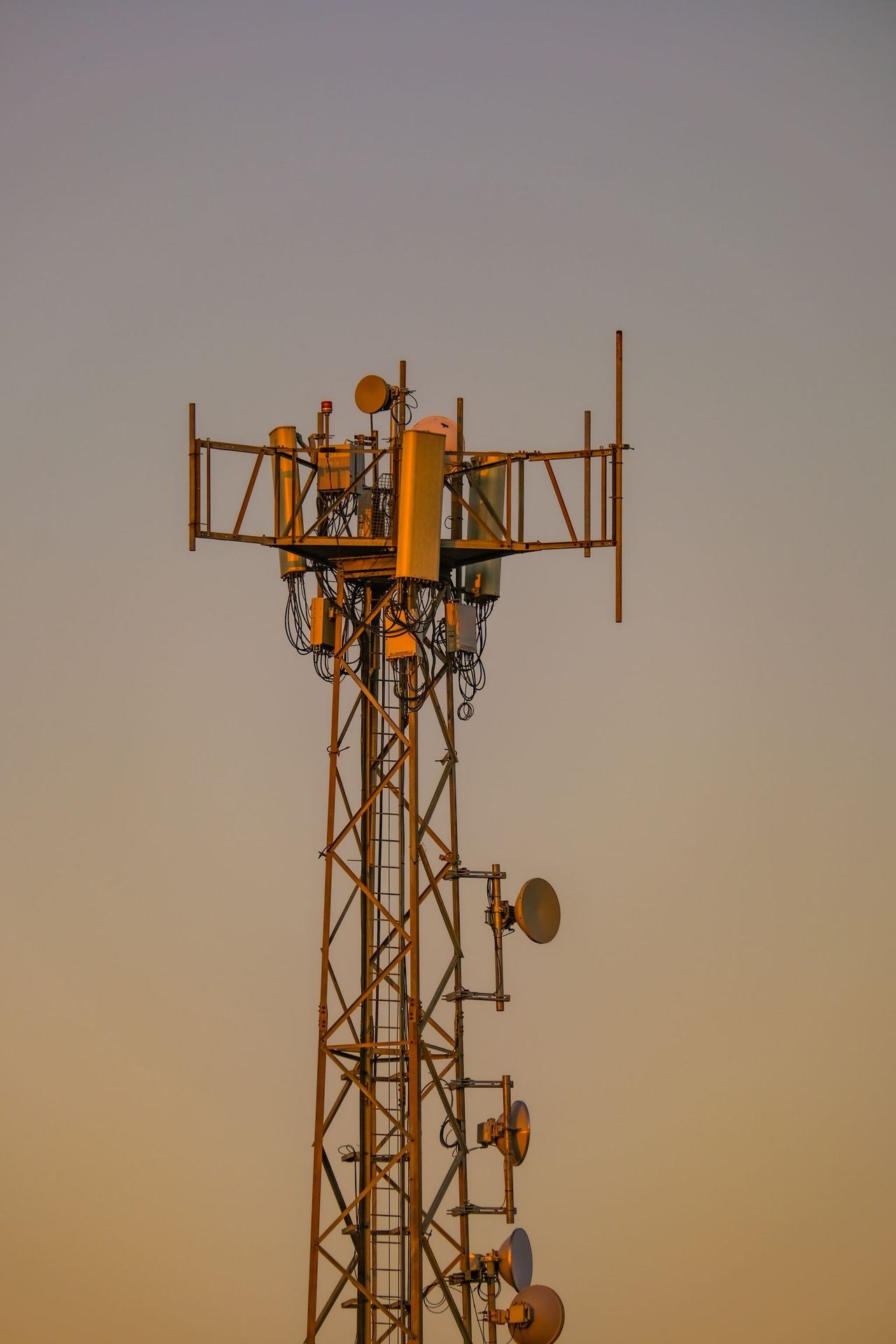 Lattice telecommunications mast with antennas against an evening sky
