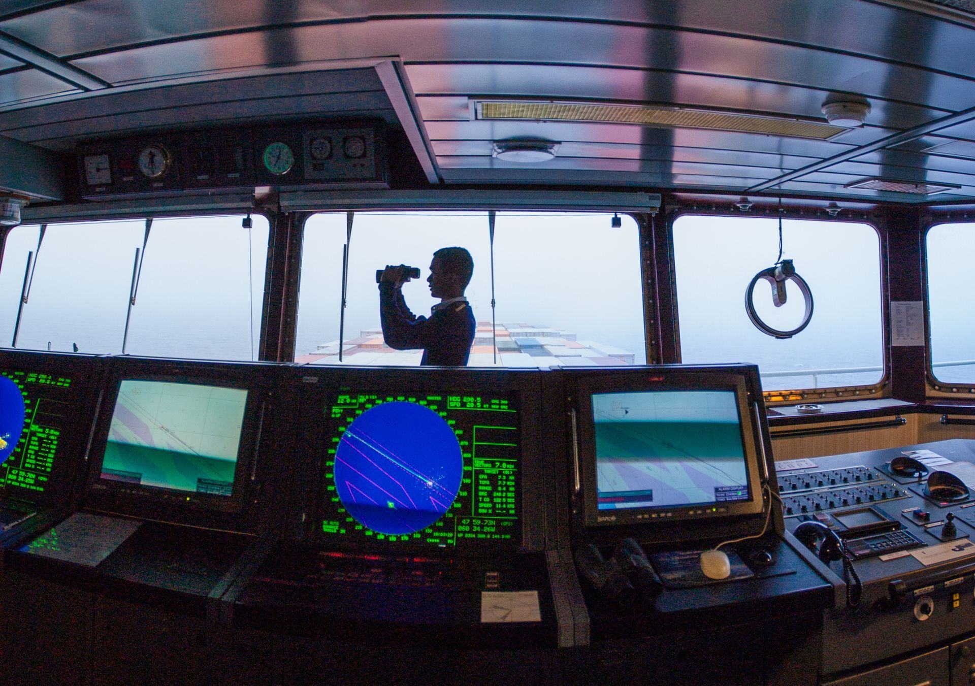 Officer on a ship’s bridge beside navigation screens